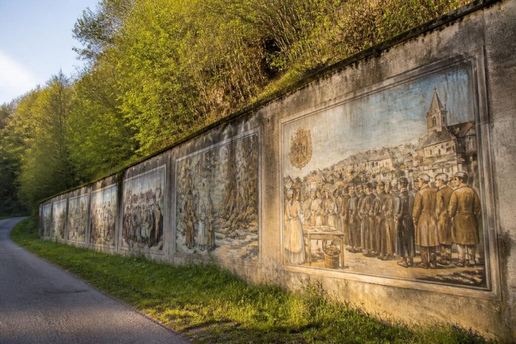 découvrez comment le mur de béton le long de la d55b au poizat-lalleyriat se métamorphose en une galerie d'art historique à ciel ouvert, alliant culture et patrimoine local.